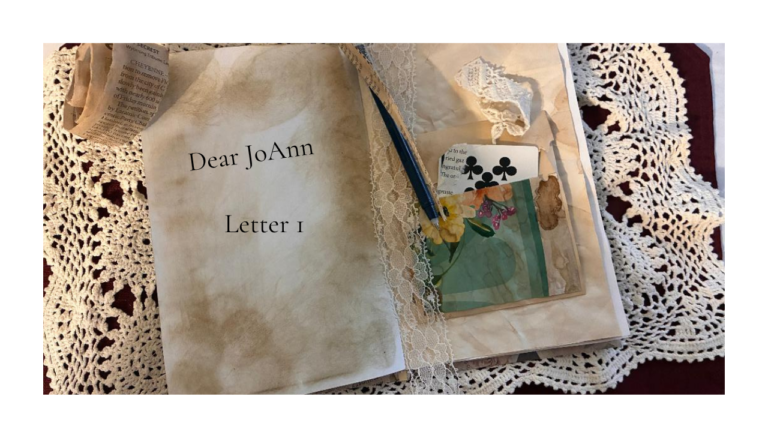 A vintage open journal on a lace tablecloth with soft, tea‑stained pages. The left page reads “Dear JoAnn — Letter No. 1,” and the right page holds lace trim, a floral paper scrap, a playing card, and a blue pen.