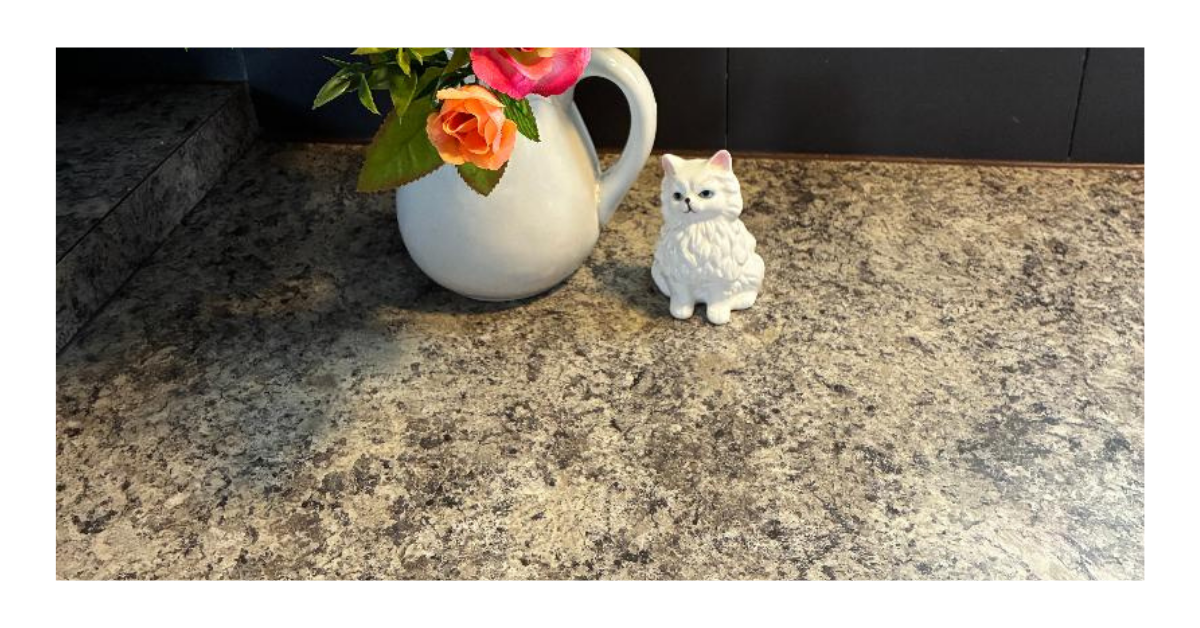 A clean kitchen counter with a white pitcher of colorful flowers and a small cat figurine — a simple intentional home reset